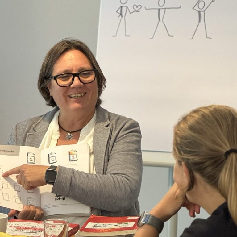 Coaching ganz individuell Frau zeigt Zeichnungen und erklärt etwas einem Zuhörer in einem Seminar.