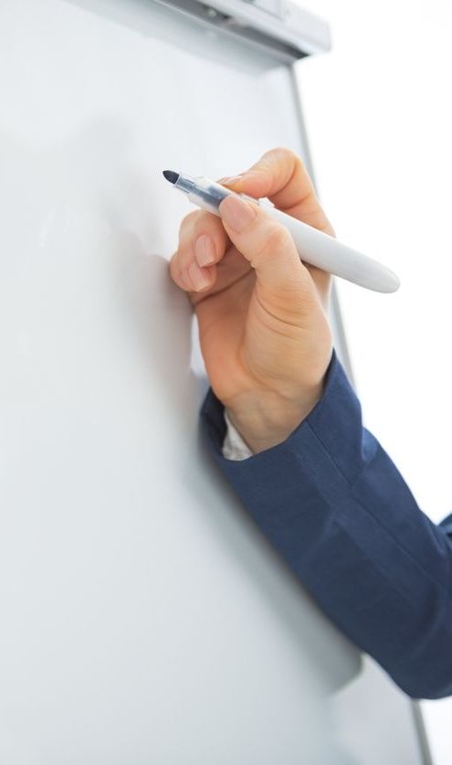 Visualisierung am Flipchart Hand mit einem Marker, die auf ein leeres Flipchart schreibt.