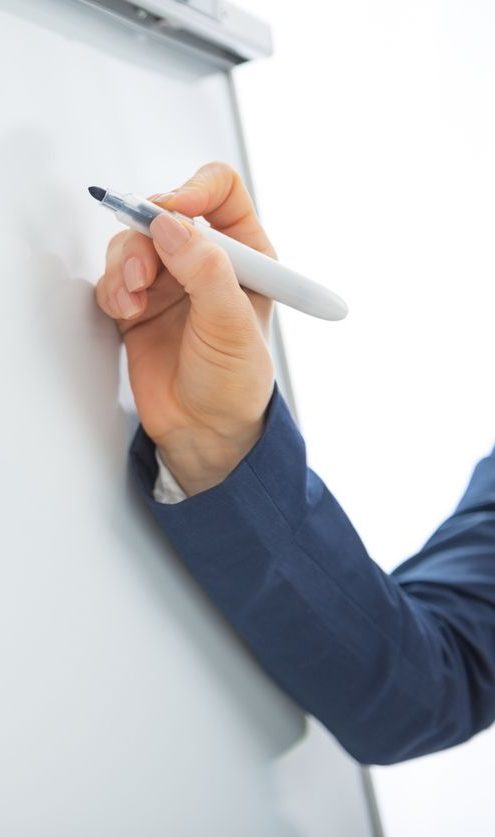 Visualisierung am Flipchart Hand mit einem Marker, die auf ein leeres Flipchart schreibt.