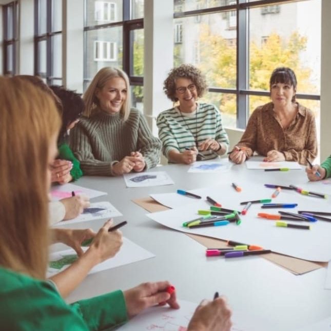 Teamcoaching und Teamentwicklung Team halten sich an den Händen, umgeben von Händen, die ihnen Halt geben.